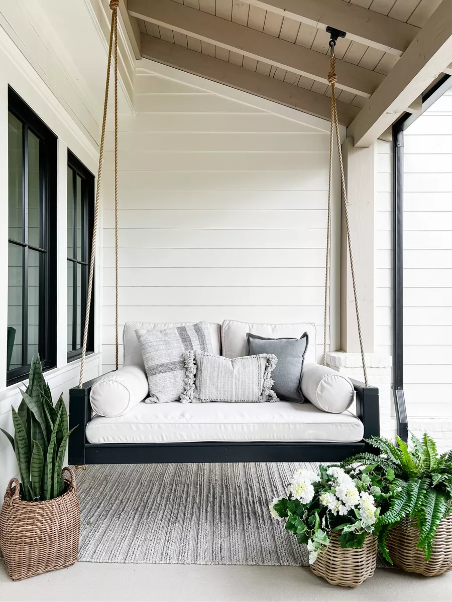 outdoor porch swing with plants around the rug